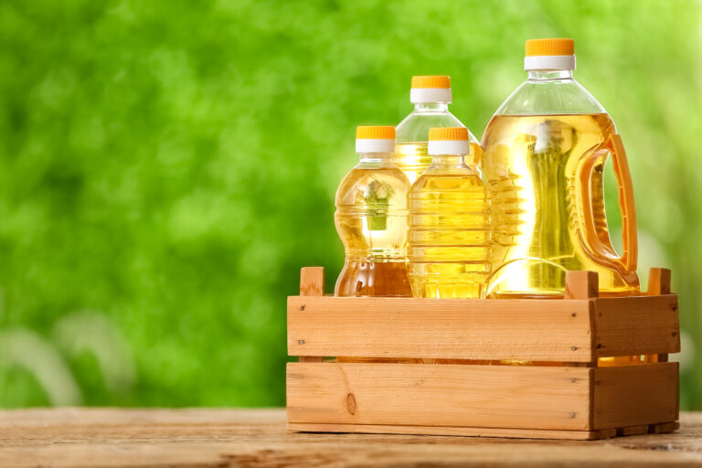 Box with bottles of sunflower oil on table outdoors